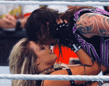 a man with a tattoo on his arm kisses a woman in a ring