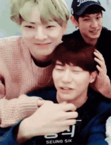 three young men are posing for a picture and one of them is wearing a seung sik shirt