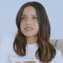 a woman sitting on a couch wearing a white shirt that says ' i 'm sorry ' on it