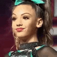a cheerleader with a bow in her hair is smiling .