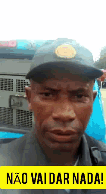 a man wearing a hat is standing in front of a sign that says não vai dar nada