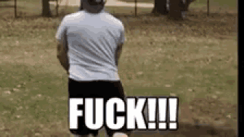 a man in a white shirt and black shorts is standing in a park with the word fuck written on the ground .